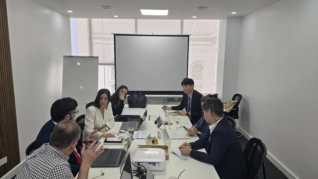 Reunión de trabajo en las oficinas de Buenos Aires con la delegación de la central de G-CERTI en Corea, alrededor de una mesa con computadoras portátiles